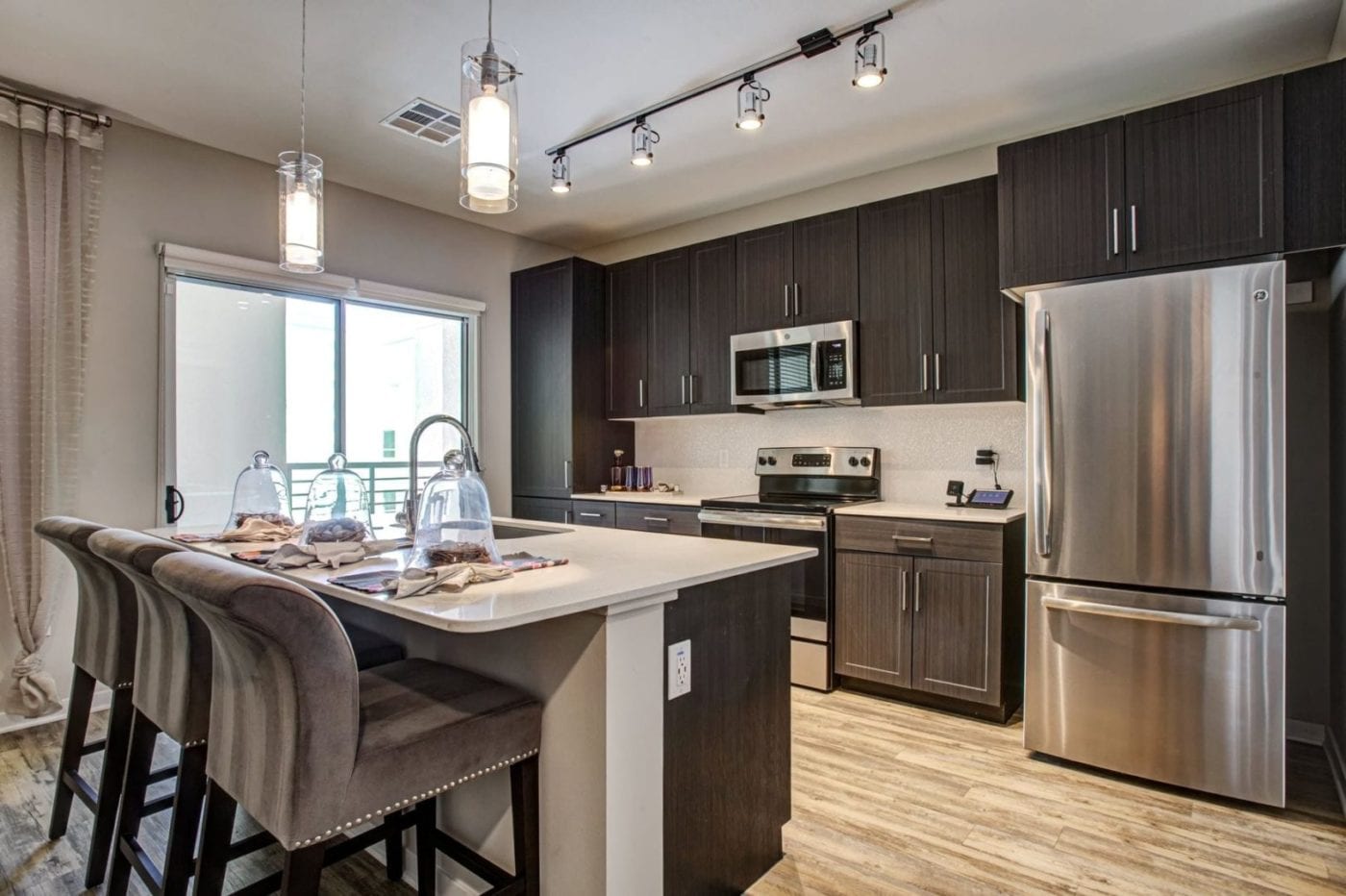 Phoenix, AZ Apartments for Rent - Large Open-Concept Kitchen with Island, Dark Cabinets, Wood Flooring and Stainless Steel Appliances.
